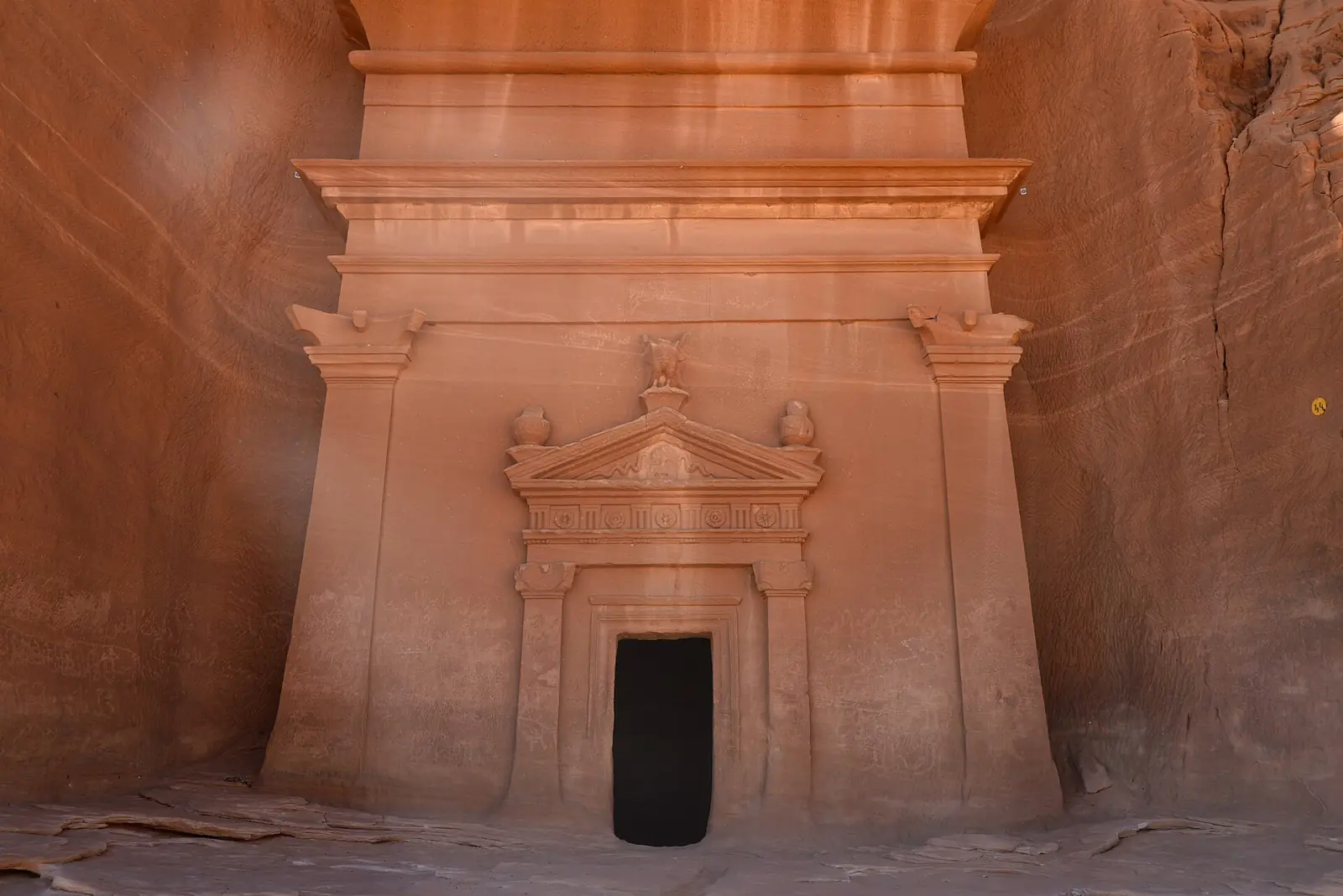A row of carved Nabataean tomb facades in a sandstone outcrop at Hegra